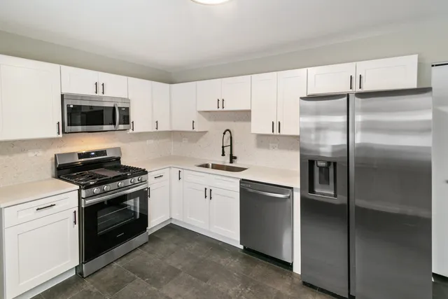 a kitchen with stainless steel appliances granite countertop a stove a sink and a refrigerator