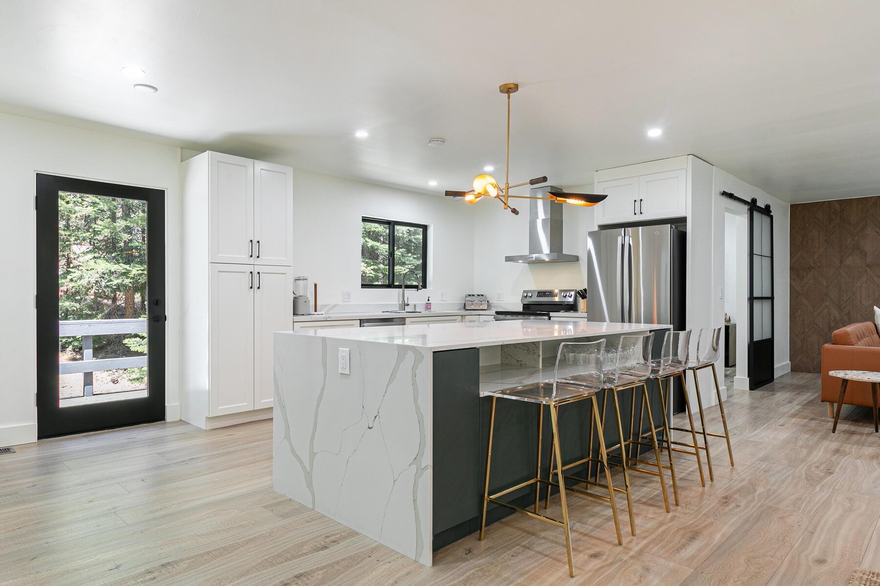 a kitchen with kitchen island granite countertop a refrigerator a stove a sink a dining table and chairs with wooden floor