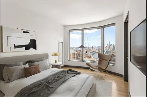 a bedroom with a bed and large windows