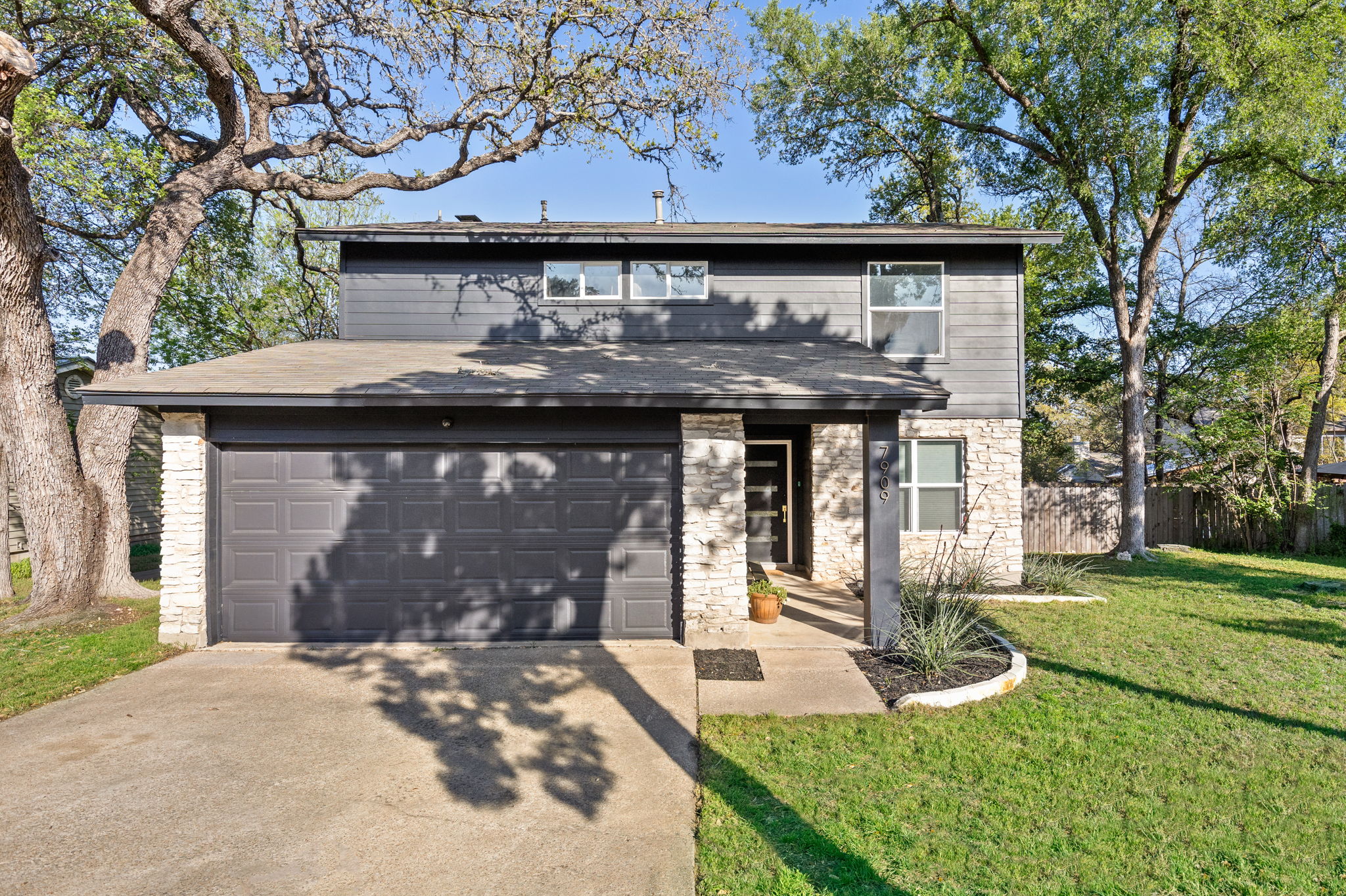 7909 Manassas Drive Austin, TX 78745 - Photo 2 of 37 Traditional-style home with stone siding, concrete driveway, and a garage