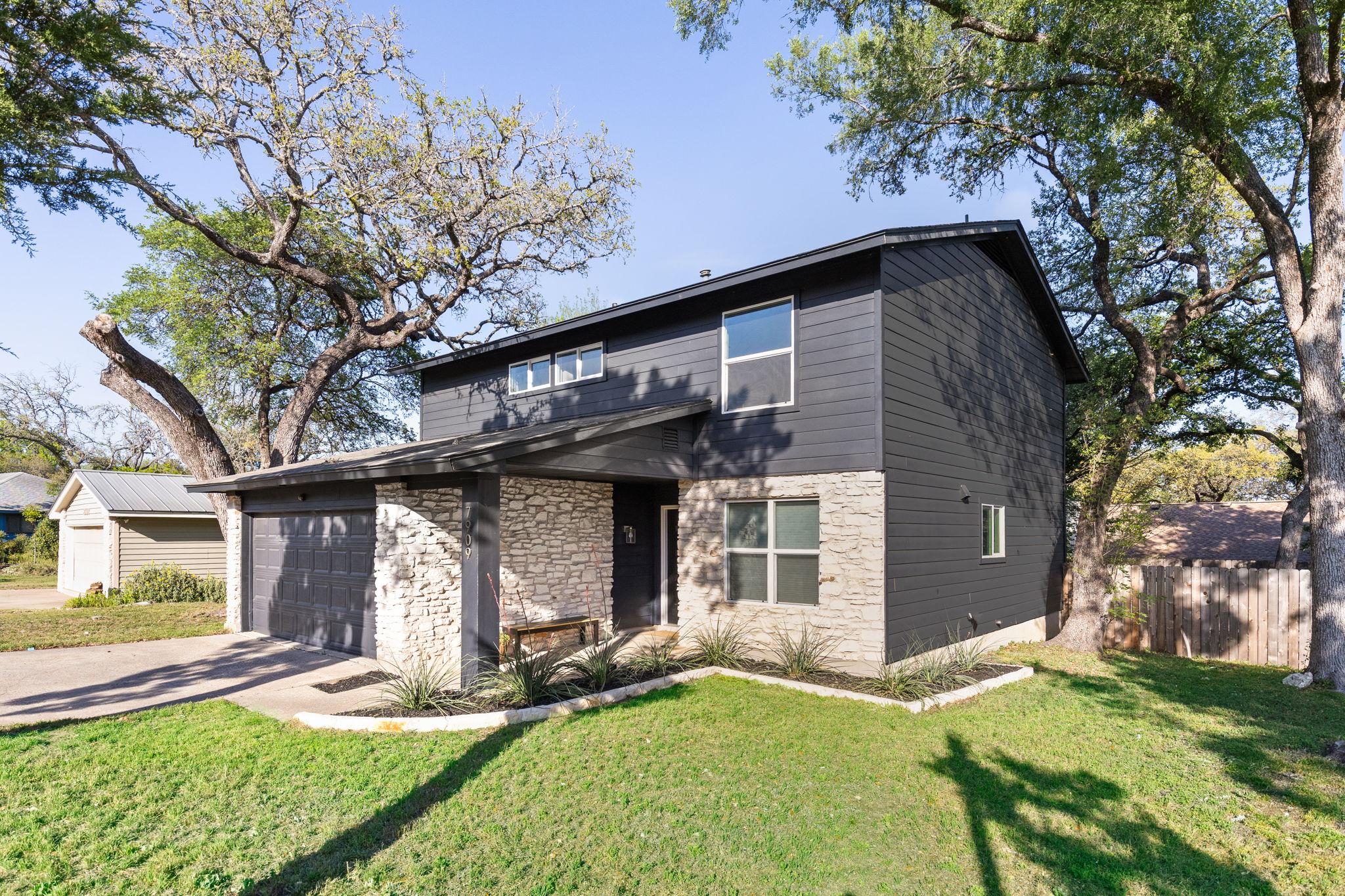 7909 Manassas Drive Austin, TX 78745 - Photo 3 of 37 View of front of house with stone siding, driveway, and an attached garage