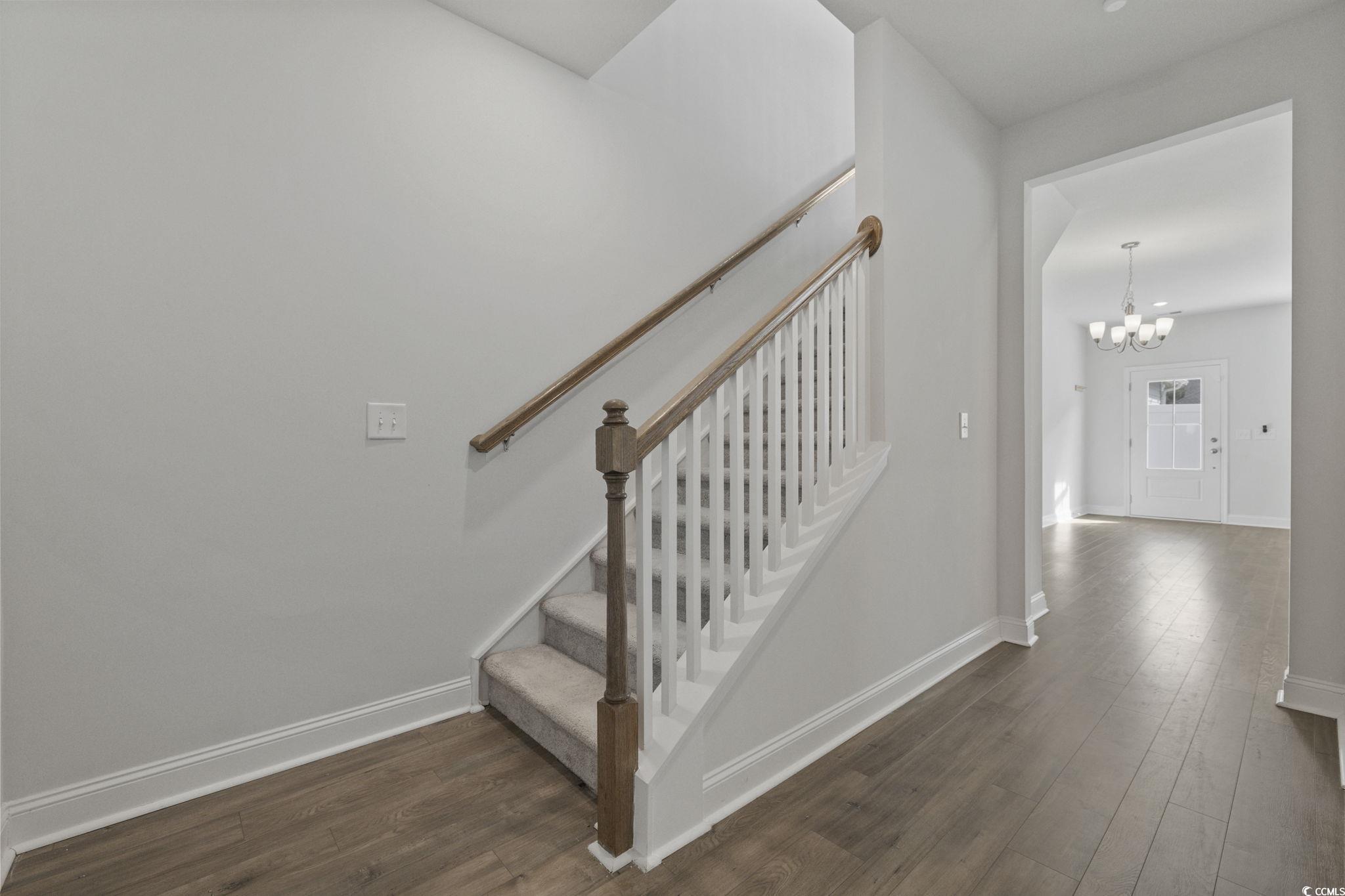 2595 Blue Crane Circle, Unit 102 Myrtle Beach, SC 29577 - Photo 22 of 40 Stairway with hardwood / wood-style flooring and a chandelier