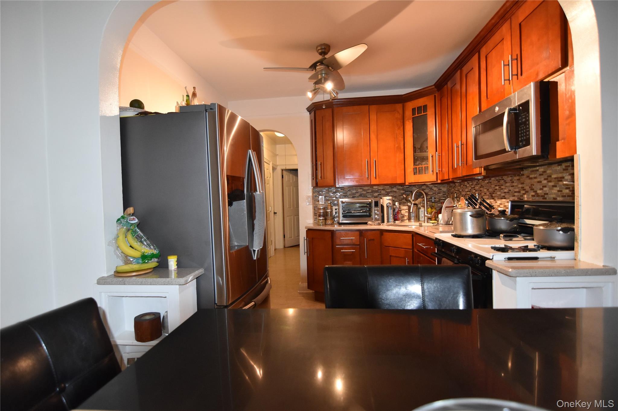 25-48 89th Street Queens, NY 11369 - Photo 4 of 17 a kitchen with a sink a refrigerator and a stove top oven with wooden floor