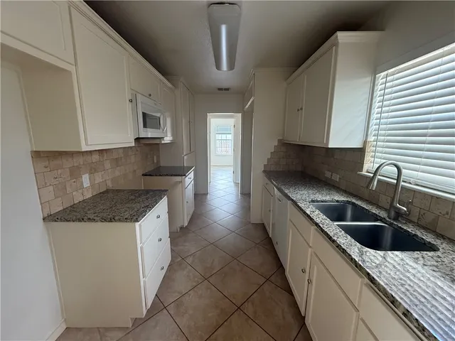 a kitchen with granite countertop a sink and white cabinets