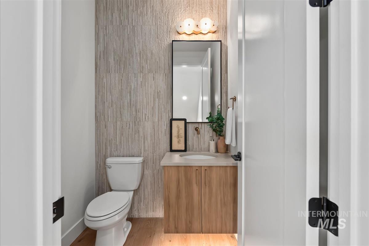 3219 West Moore Street Boise, ID 83702 - Photo 19 of 36 Powder room featuring a wood-finish vanity with an undermount sink, a framed mirror, and a sconce light fixture