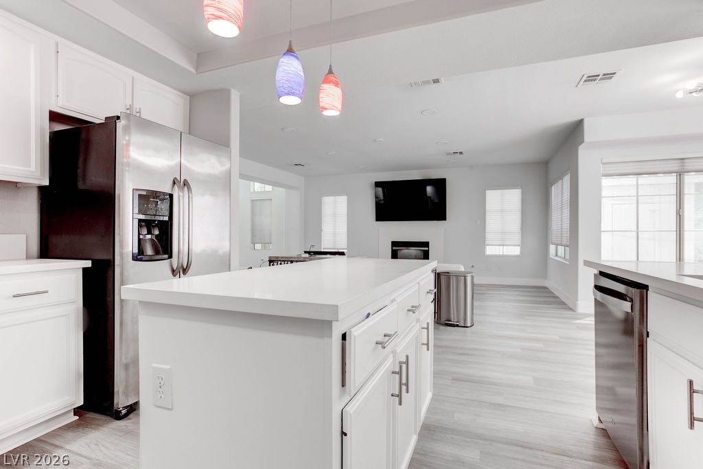 1 Rising Sun Court Henderson, NV 89074 - Photo 10 of 47 A pristine, well-lit kitchen with a spacious island connects seamlessly to a modern living area.