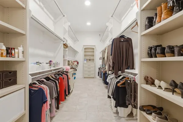 a view of walk in closet with clothes and shoes