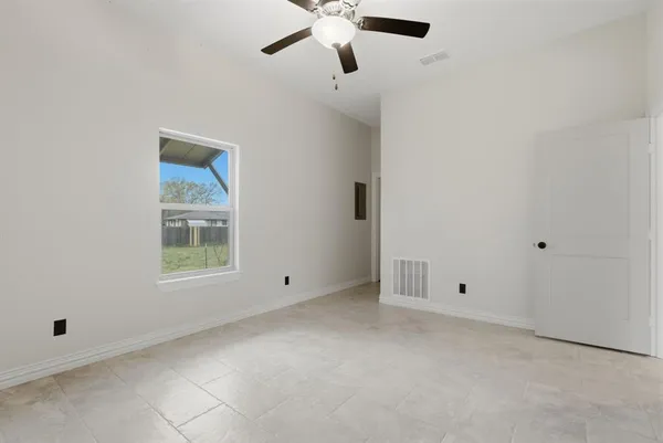 an empty room with windows and fan