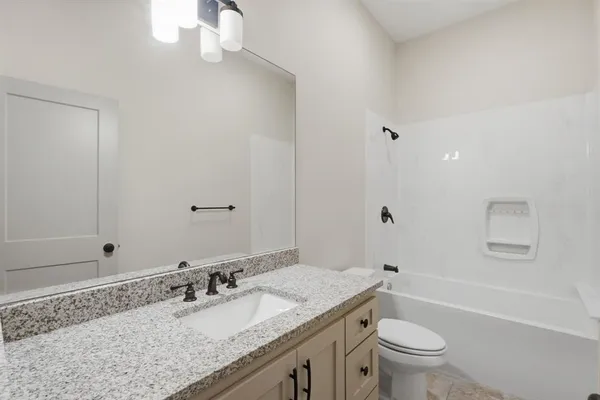 a bathroom with a granite countertop sink a toilet and bathtub