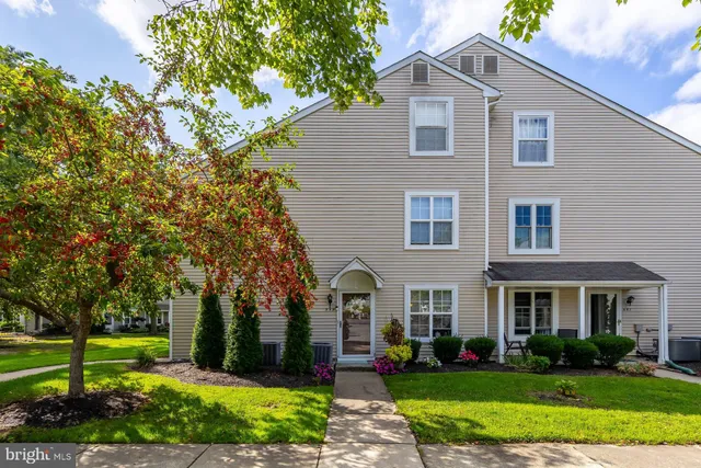 a front view of a house with garden and trees