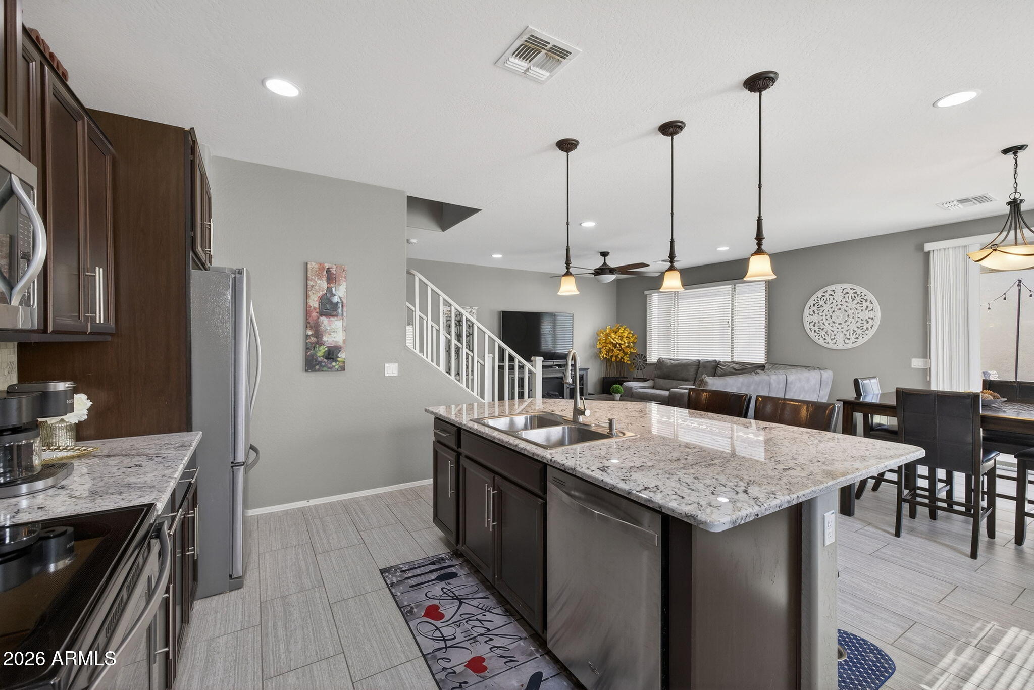 921 South Swallow Lane Gilbert, AZ 85296 - Photo 12 of 36 a kitchen with granite countertop kitchen island stainless steel appliances a table chairs sink and stove