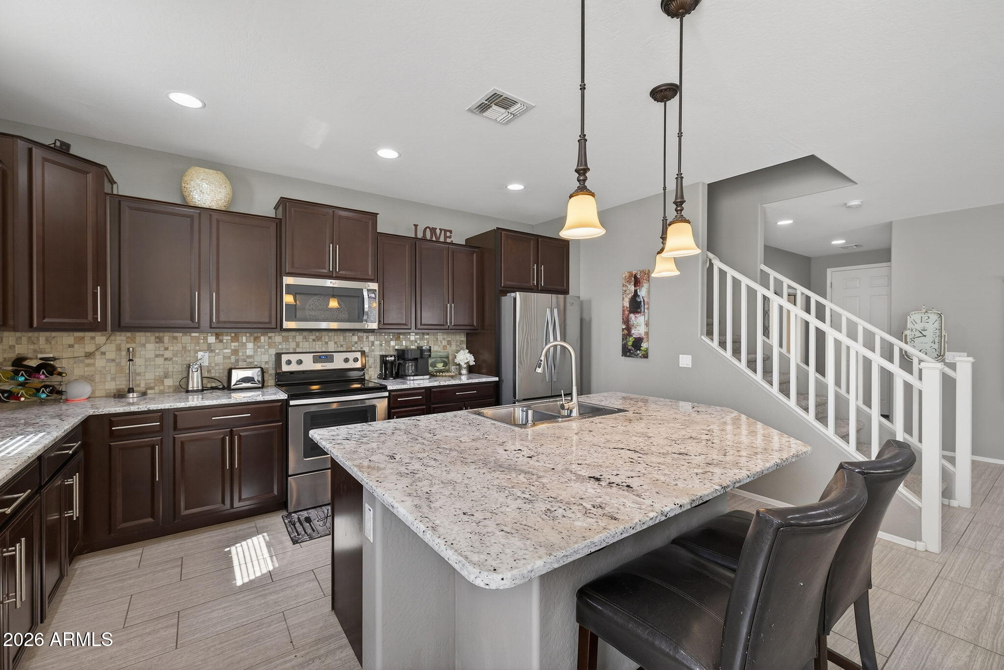 921 South Swallow Lane Gilbert, AZ 85296 - Photo 9 of 36 a kitchen with stainless steel appliances granite countertop a kitchen island a stove a sink a dining table and chairs