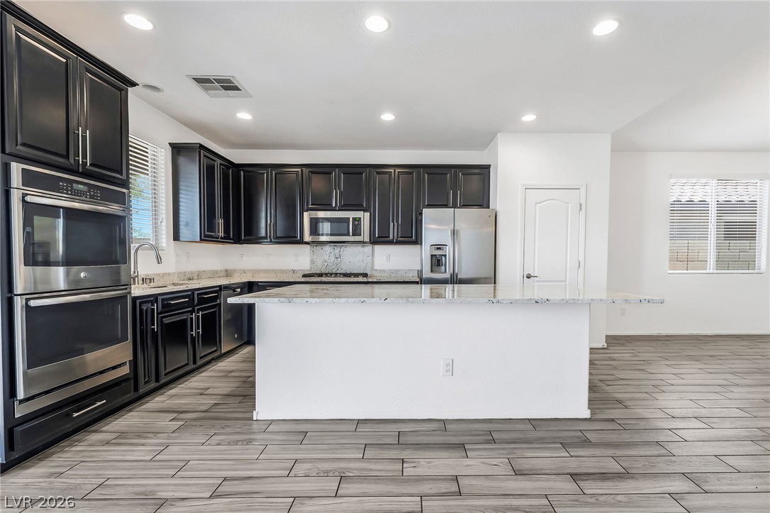 6245 Andover Wood Road Las Vegas, NV 89113 - Photo 9 of 37 A well-appointed culinary space showcasing dark cabinetry, granite countertops, and modern appliances.