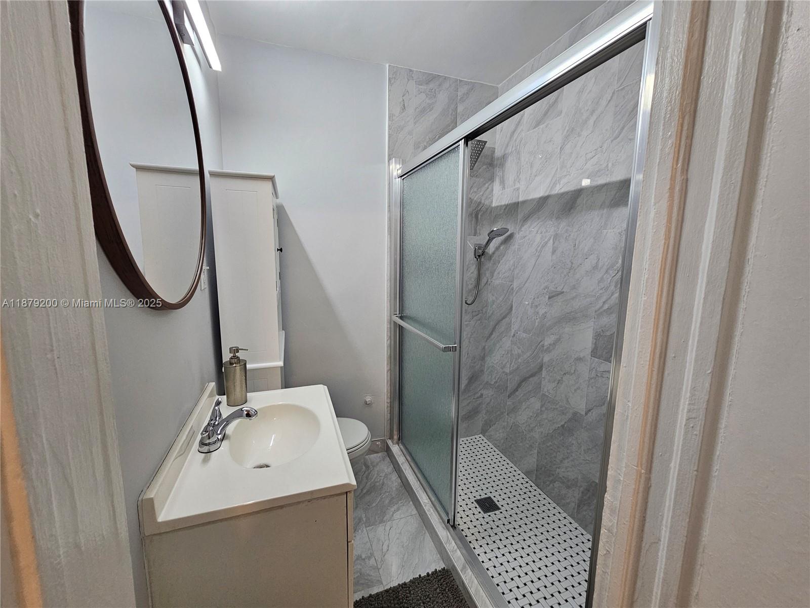 1265 Southwest 4th Street, Unit 4 Miami, FL 33130 - Photo 21 of 24 a bathroom with a sink a glass door shower and a mirror