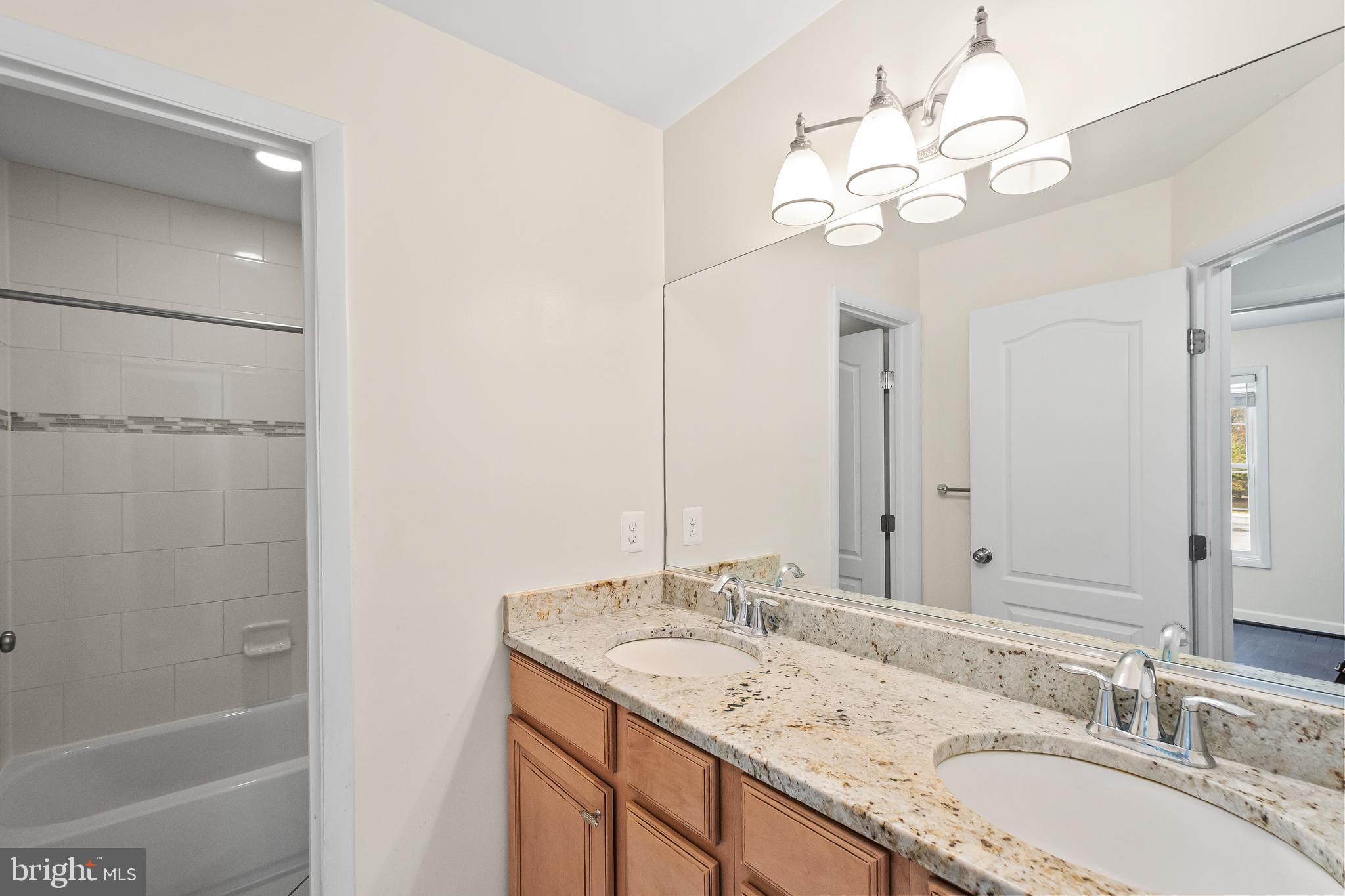 7872 Azalea Cove Terrace Alexandria, VA 22315 - Photo 26 of 30 a bathroom with a granite countertop sink a large mirror and a shower