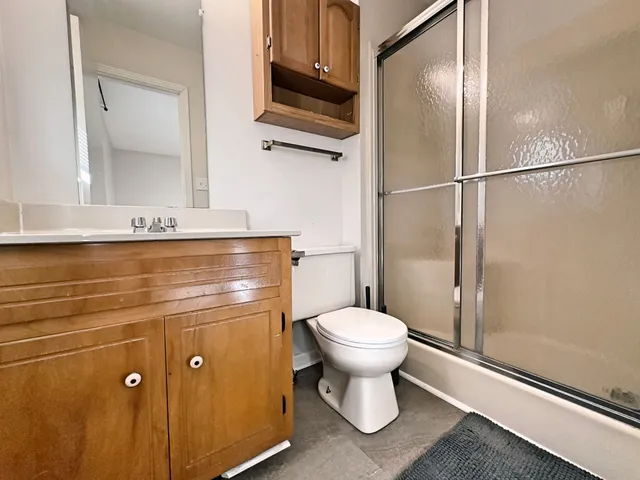 a bathroom with a granite countertop toilet a sink and a mirror