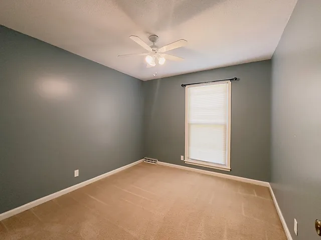 an empty room with a window and a fan