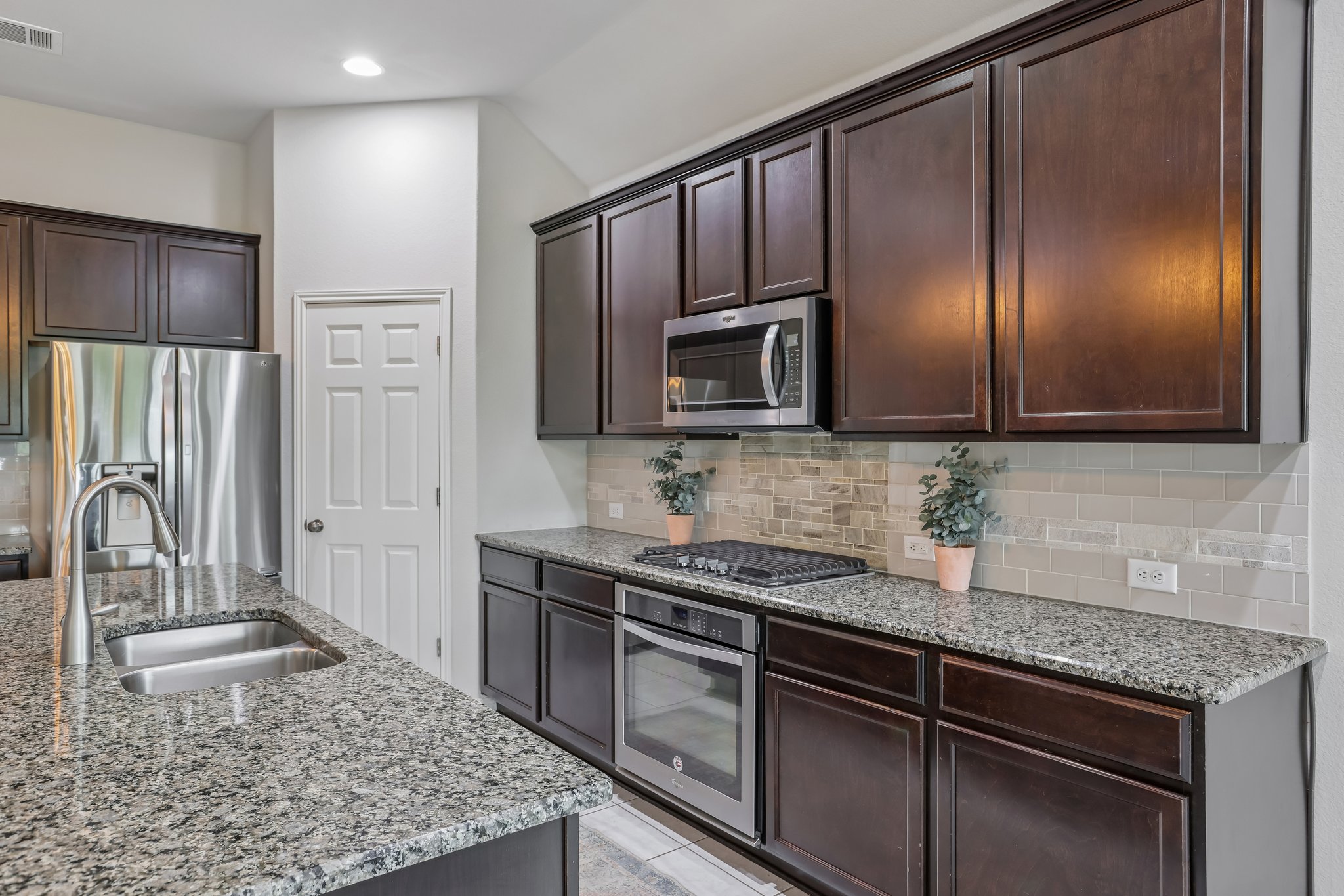 6801 Banff Cove Austin, TX 78754 - Photo 7 of 37 Wood cabinetry, stainless steel appliances, and an island with a sink