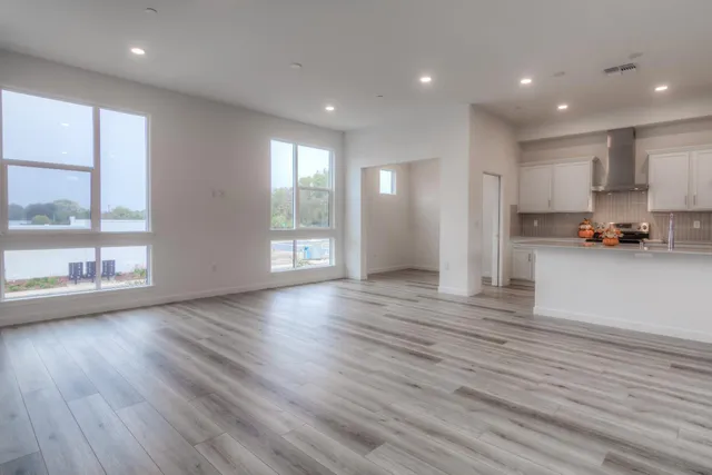 an empty room with wooden floor and windows
