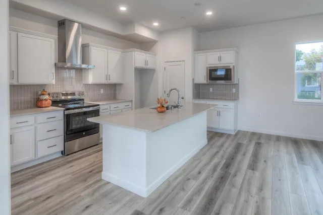 a kitchen with stainless steel appliances granite countertop a stove a sink dishwasher and a refrigerator with wooden floor