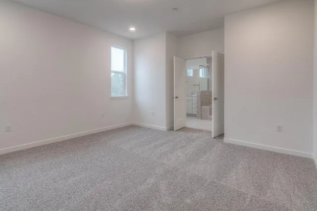 an empty room with window in back and closet area