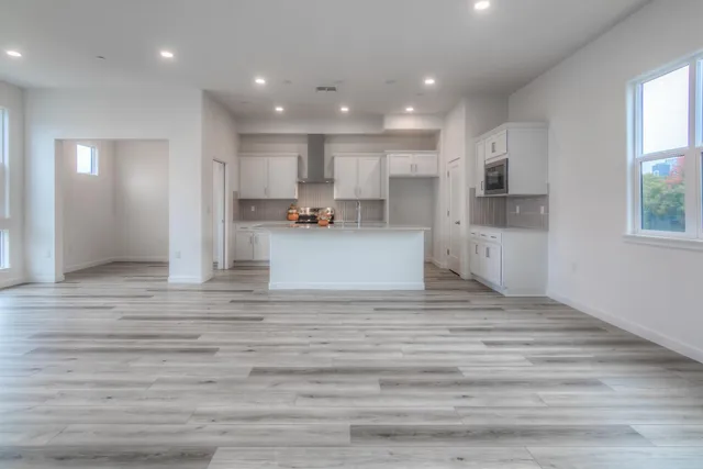 a view of kitchen with kitchen island stainless steel appliances wooden floor cabinets and a window