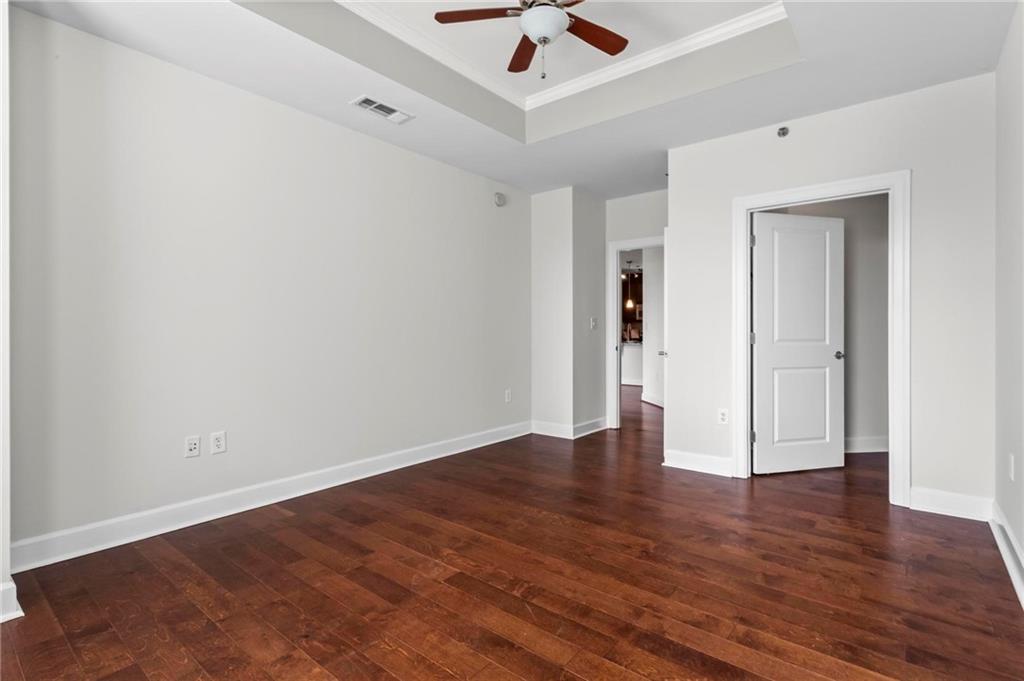 325 East Paces Ferry Road Northeast, Unit 703 Atlanta, GA 30305 - Photo 18 of 31 an empty room with wooden floor and ceiling fan