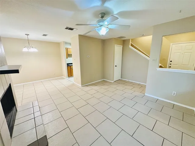 a view of an empty room and chandelier fan