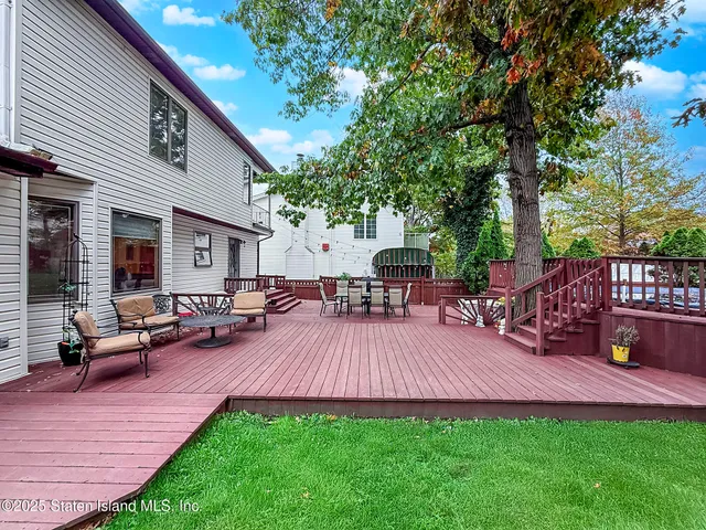 a view of a patio with table and chairs potted plants and a large tree