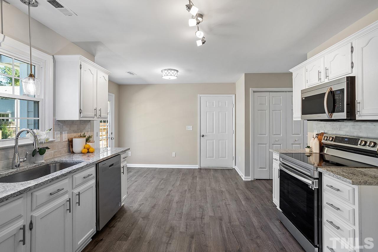 3537 Limber Lane Raleigh, NC 27616 - Photo 6 of 30 a kitchen with stainless steel appliances a stove top oven a sink dishwasher and a refrigerator with wooden floor