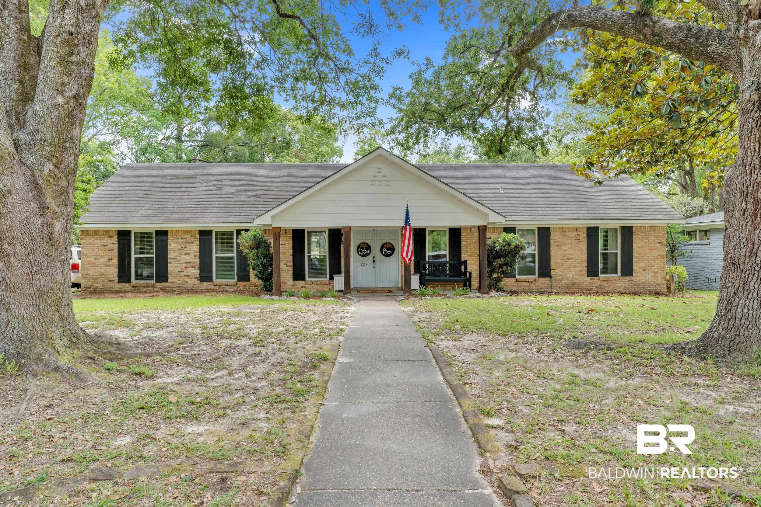 224 Cache Circle Mobile, AL 36611 - Photo 1 of 42 Ranch-style home with covered porch, brick siding, roof with shingles, and a front lawn