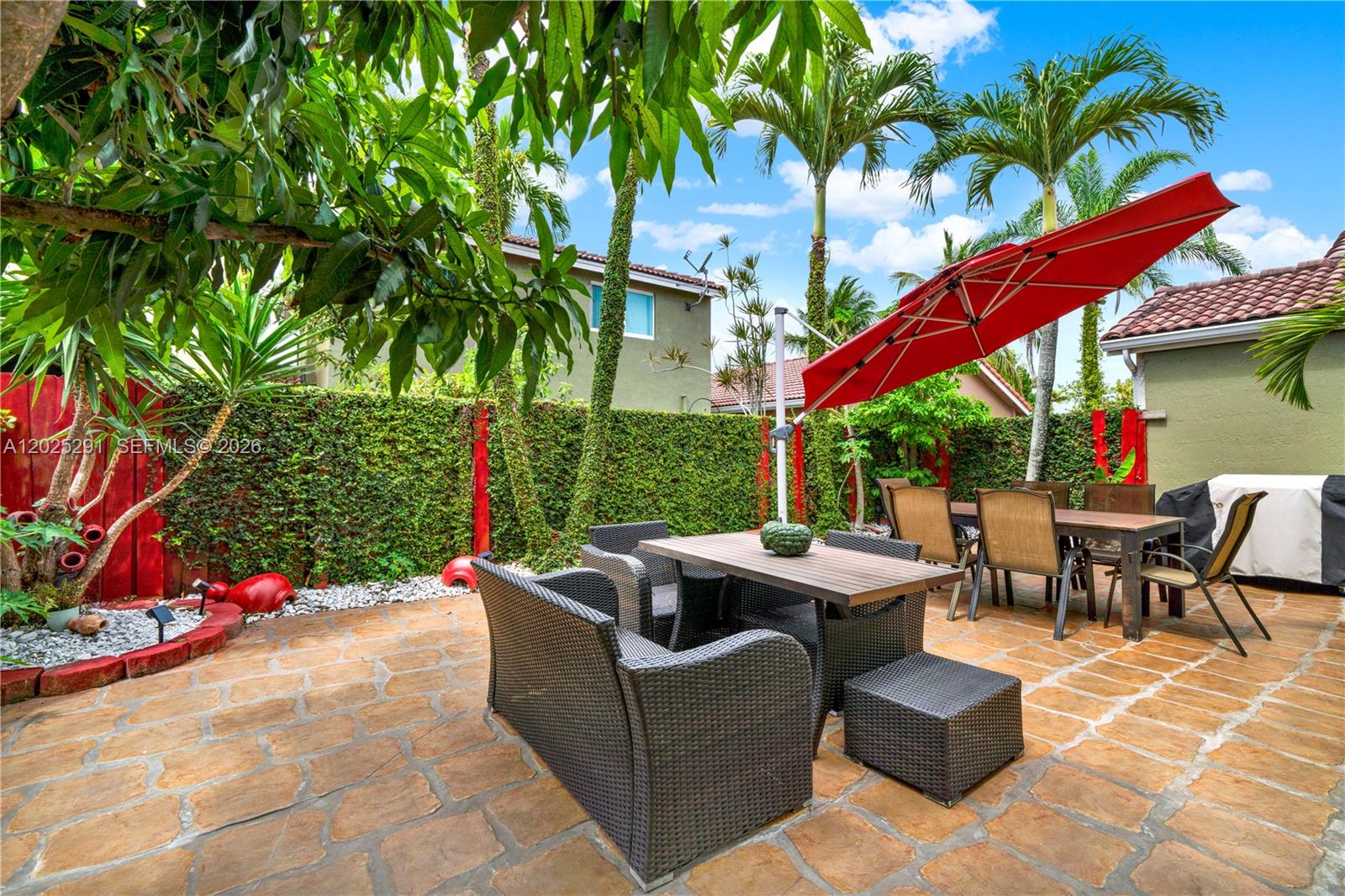 10006 Southwest 162nd Path Miami, FL 33196 - Photo 32 of 40 a view of a patio with couches and table and chairs under an umbrella
