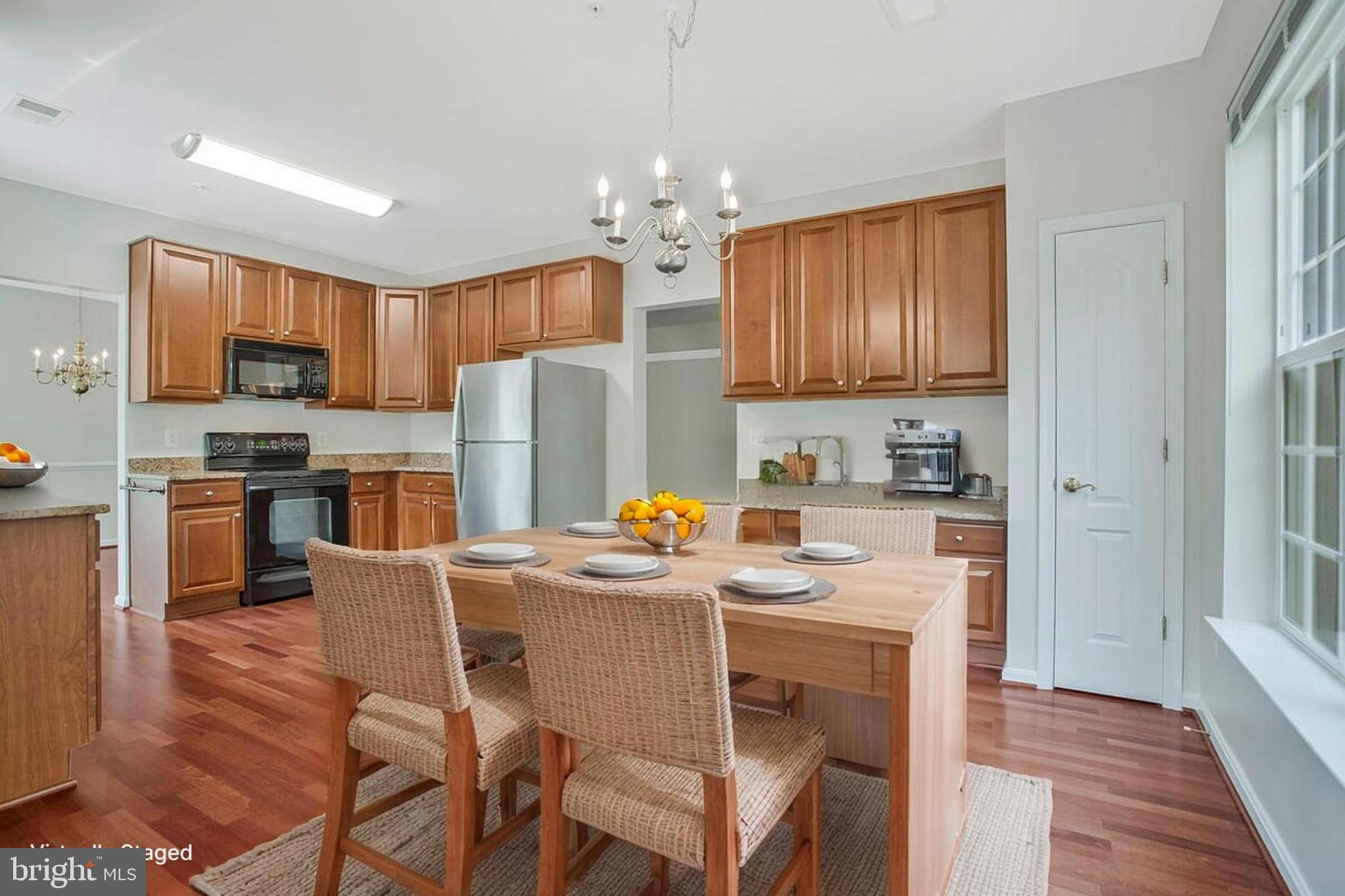 7305 Maplecrest Road, Unit 206 Elkridge, MD 21075 - Photo 17 of 62 a kitchen with stainless steel appliances granite countertop a refrigerator a stove top oven a sink dishwasher and a dining table with wooden floor