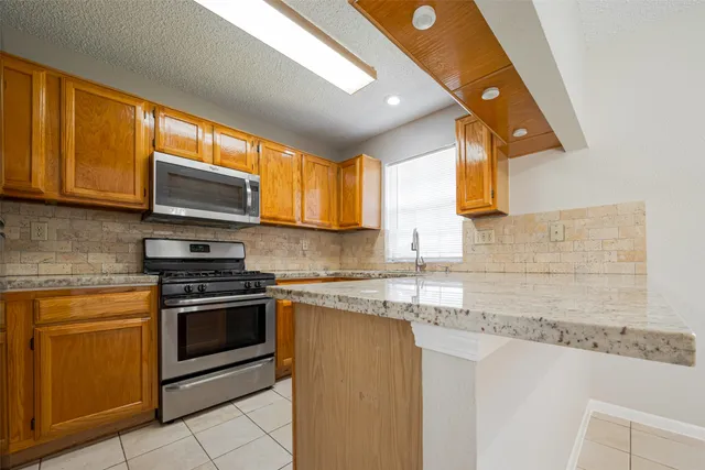 a kitchen with stainless steel appliances granite countertop a sink stove and microwave