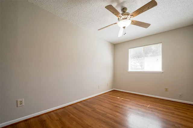 an empty room with a window and a ceiling fan