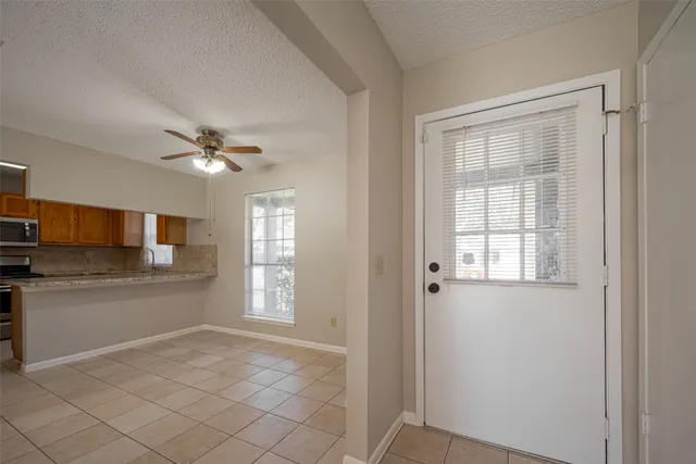 a view of a kitchen and an empty room with wooden floor and windows