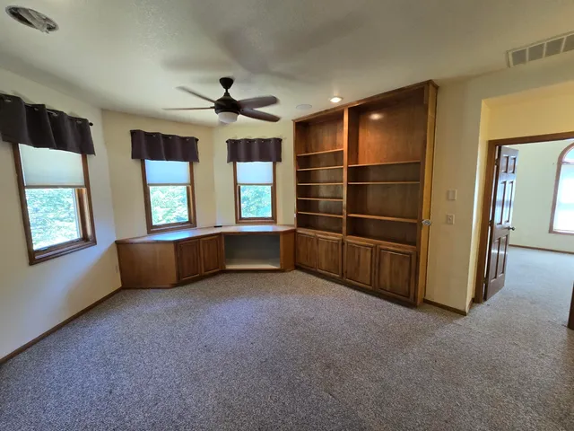 an empty room with windows and fireplace