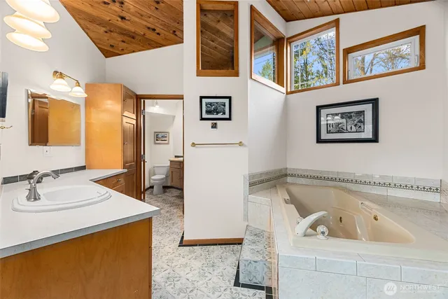 a bathroom with a tub a sink and a mirror