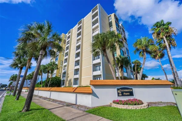 front view of house with a yard and palm trees