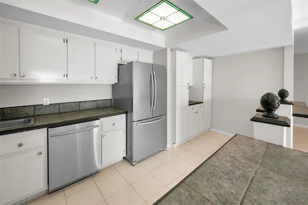 a kitchen with granite countertop white cabinets and stainless steel appliances