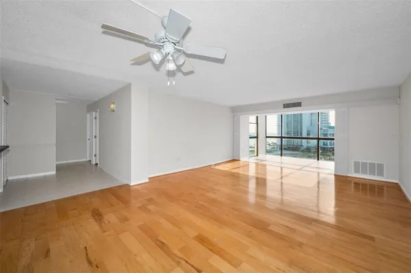 a view of an empty room with wooden floor and a window