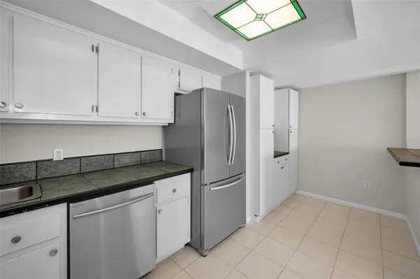 a kitchen with white cabinets and refrigerator