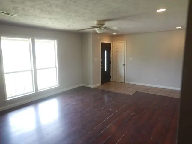 an empty room with wooden floor and windows