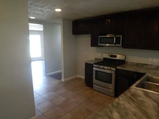 a kitchen with stainless steel appliances a stove a microwave and sink