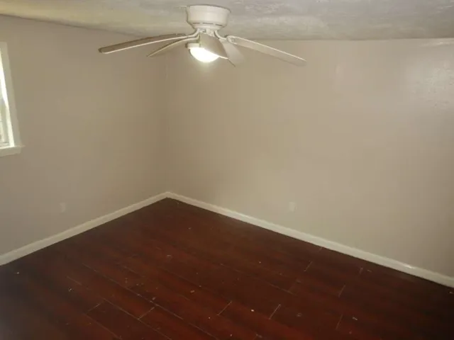 en empty room with wooden floor and fan