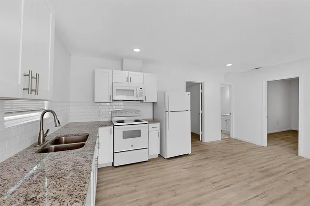 a kitchen with granite countertop a sink stove and refrigerator