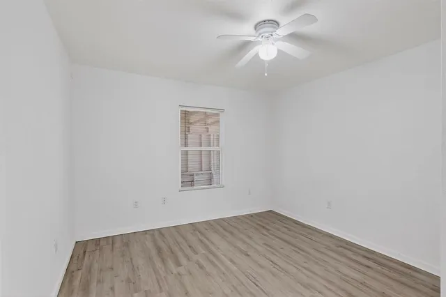 an empty room with a window and a fan