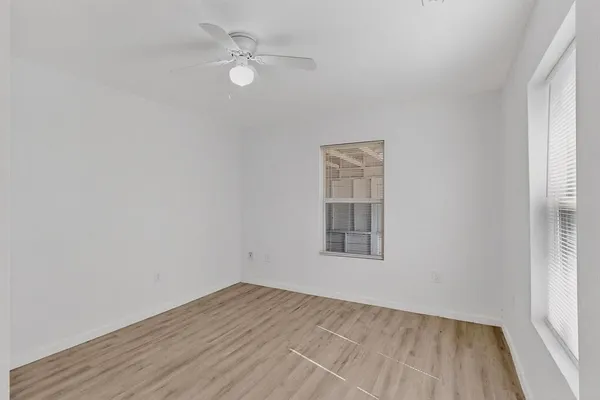 an empty room with a window and ceiling fan