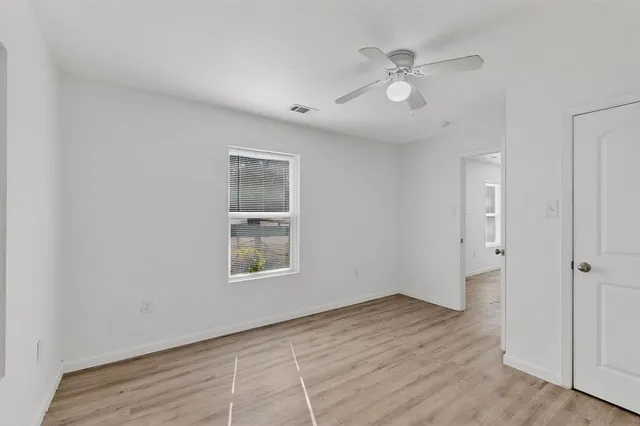 an empty room with wooden floor and windows