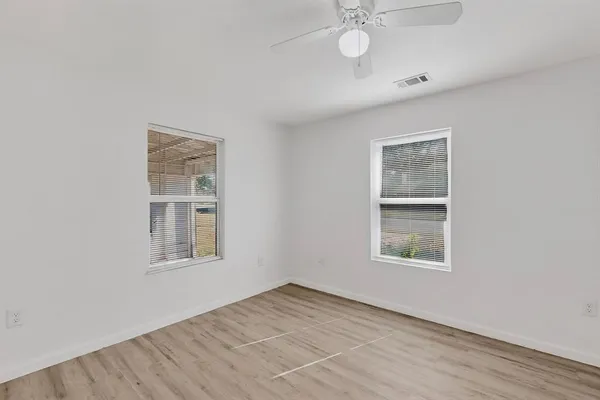 an empty room with windows and fan